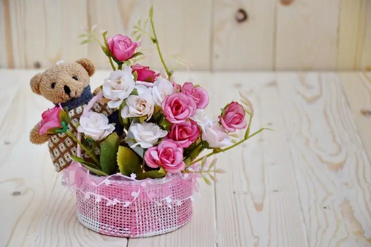 Un bouquet de fleur agrémenté d'un petit nounours en peluche